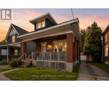 A house with a porch and a fence in front of it.