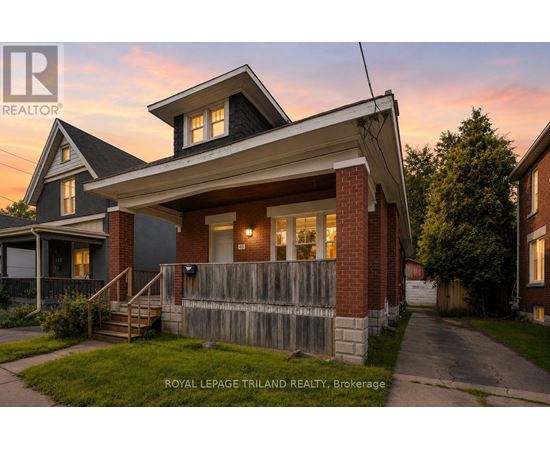 A house with a porch and a fence in front of it.
