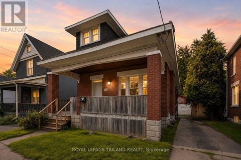 A house with a porch and a fence in front of it.