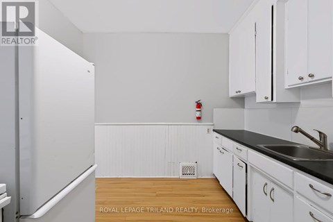 A kitchen with white cabinets and a black countertop.