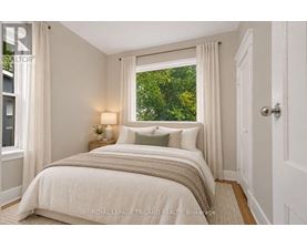 A bedroom with a large bed and a window overlooking greenery.