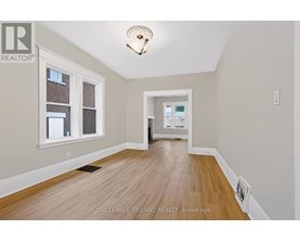 A room with wooden flooring and a window with a view of a building.