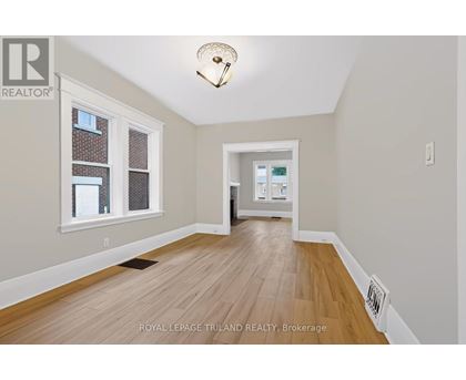A room with wooden flooring and a window with a view of a building.