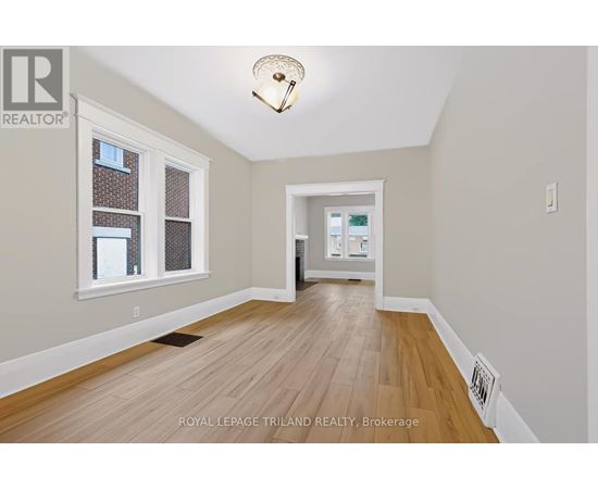 A room with wooden flooring and a window with a view of a building.