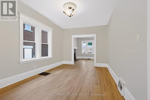 A room with wooden flooring and a window with a view of a building.