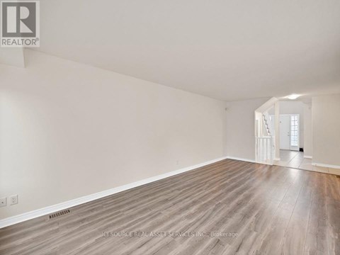 A spacious room with wooden flooring and white walls.