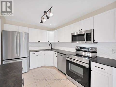 A kitchen with white cabinets and black countertops.