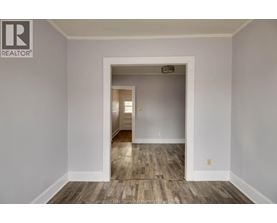 A room with a wooden floor and a white door leading to another room.