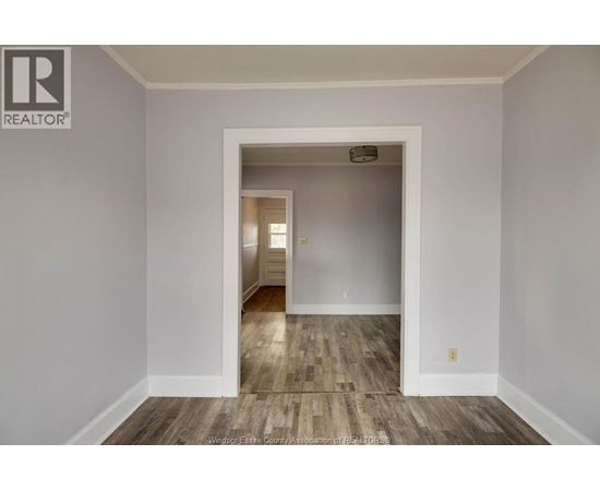 A room with a wooden floor and a white door leading to another room.