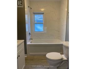 A white toilet sits next to a bathtub in a bathroom.