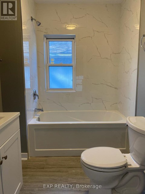 A white toilet sits next to a bathtub in a bathroom.
