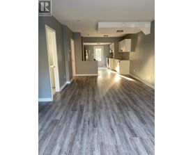 A spacious room with wooden flooring and a large mirror on the wall.