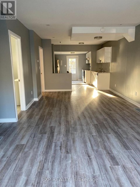 A spacious room with wooden flooring and a large mirror on the wall.