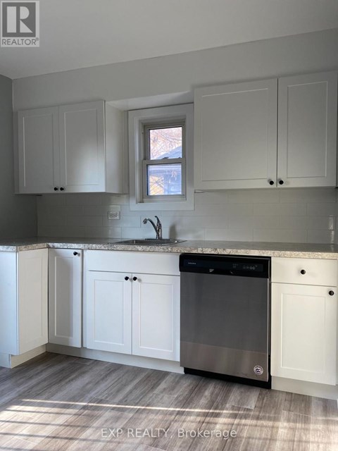 A kitchen with white cabinets and a black dishwasher.