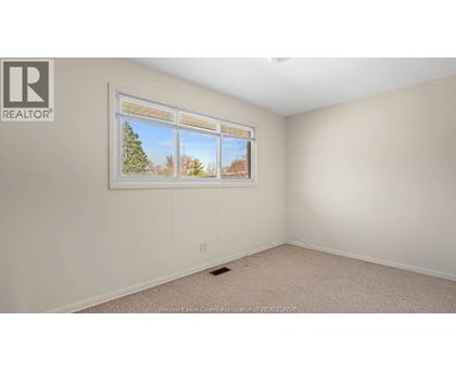A room with a window showing a view of trees and sky.