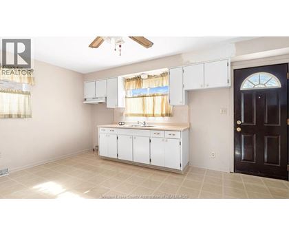 A kitchen with white cabinets and a black door.