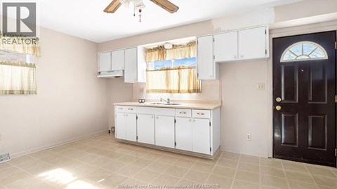 A kitchen with white cabinets and a black door.