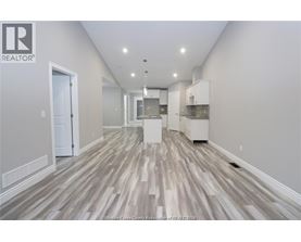 A spacious room with wood flooring and white walls.