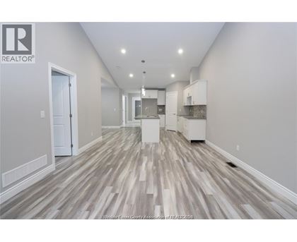 A spacious room with wood flooring and white walls.
