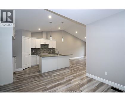 A kitchen with white cabinets and a stone backsplash.