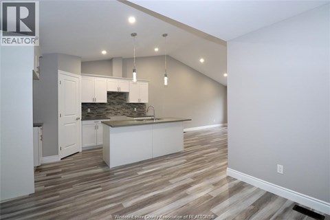 A kitchen with white cabinets and a stone backsplash.