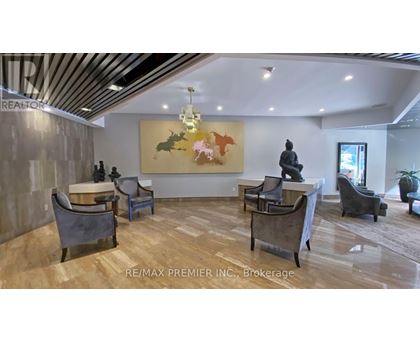 A living room with a grey couch, a coffee table, and a painting on the wall.