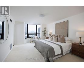 A bedroom with a large bed and a window overlooking the city.