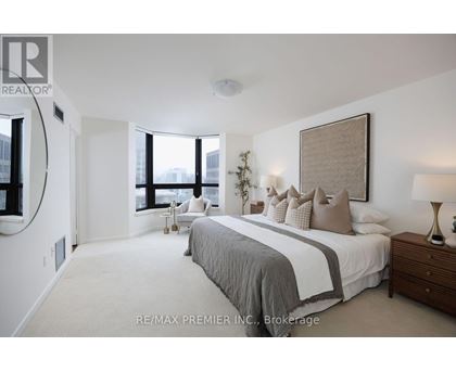 A bedroom with a large bed and a window overlooking the city.