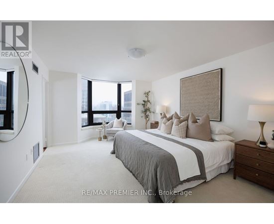 A bedroom with a large bed and a window overlooking the city.