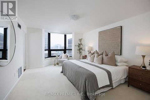 A bedroom with a large bed and a window overlooking the city.