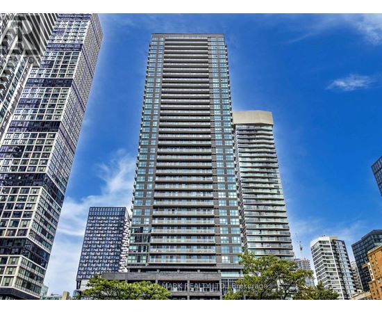 A tall building with many windows stands in front of other buildings.