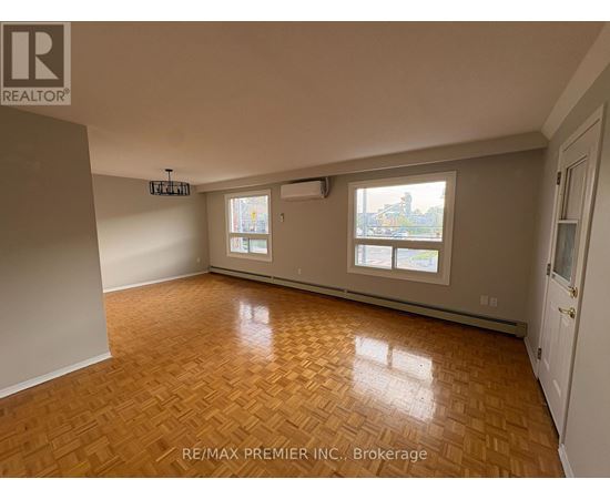A room with wooden flooring and a view of a city through the windows.