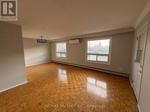 A room with wooden flooring and a view of a city through the windows.