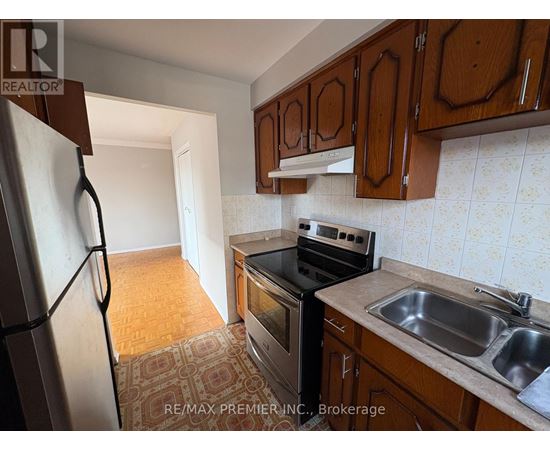 A kitchen with a refrigerator, oven, and sink.