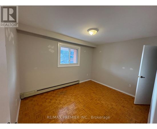 A room with wooden flooring and a window with a view of a building.