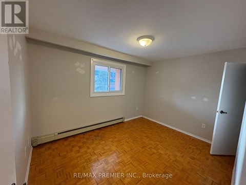 A room with wooden flooring and a window with a view of a building.