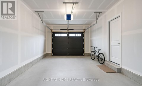A spacious garage with a bicycle and a black door.