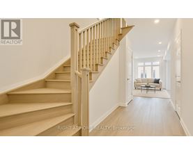 A wooden staircase leads to a bright living room.
