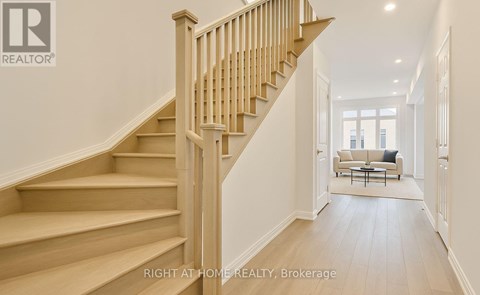 A wooden staircase leads to a bright living room.