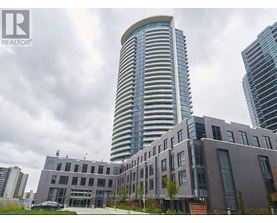 A modern building with a curved glass facade stands tall among other buildings.