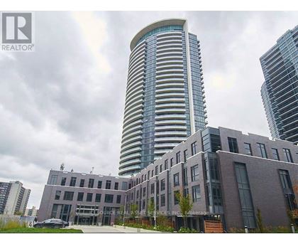 A modern building with a curved glass facade stands tall among other buildings.