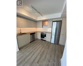 A kitchen with a refrigerator, oven, and sink.