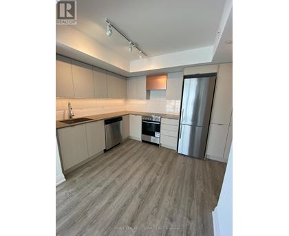 A kitchen with a refrigerator, oven, and sink.