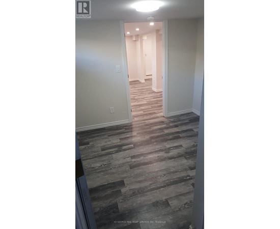 A hallway with a wooden floor and white walls.