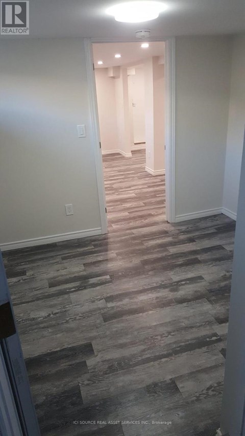 A hallway with a wooden floor and white walls.