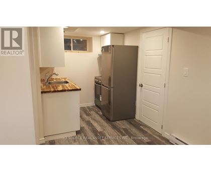 A kitchen with a refrigerator, sink, and cabinets.