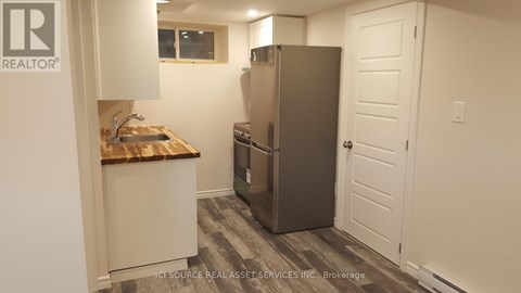 A kitchen with a refrigerator, sink, and cabinets.
