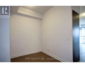 A room with white walls and wooden flooring, with a door on the right side.