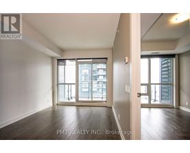 A spacious room with wooden floors and large windows overlooking a cityscape.