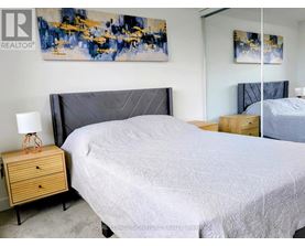 A bedroom with a large bed and a painting on the wall.